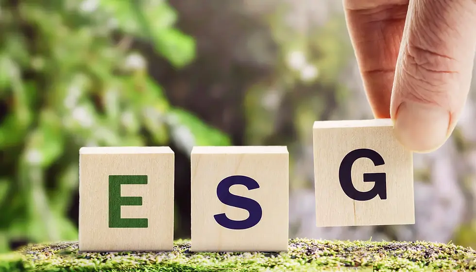Hand placing a wooden G block beside E and S blocks on moss, spelling ESG against a blurred green outdoor background.