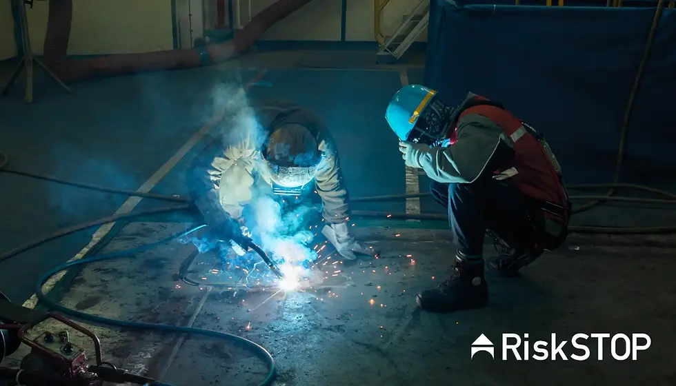 Two workers in protective gear welding, surrounded by blue sparks and smoke. Industrial setting with blue and yellow tones.
