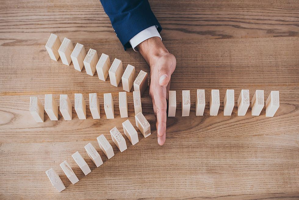 A hand interrupting a row of dominoes falling down