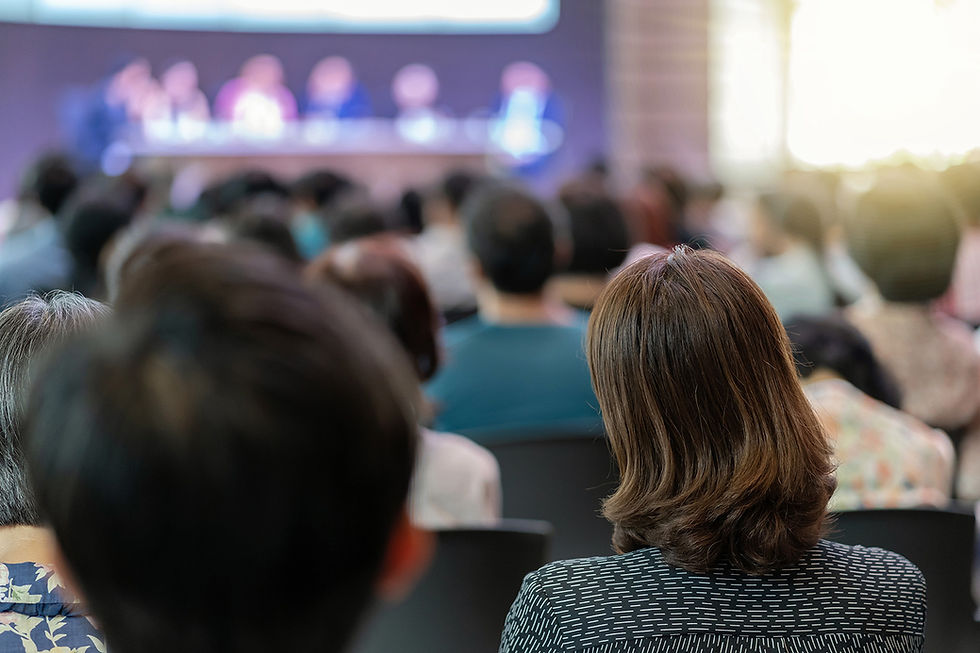 People in an auditorium listening to speakers at a conference